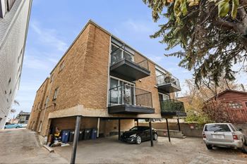A modern two-story building with a balcony and a car parked in front.
